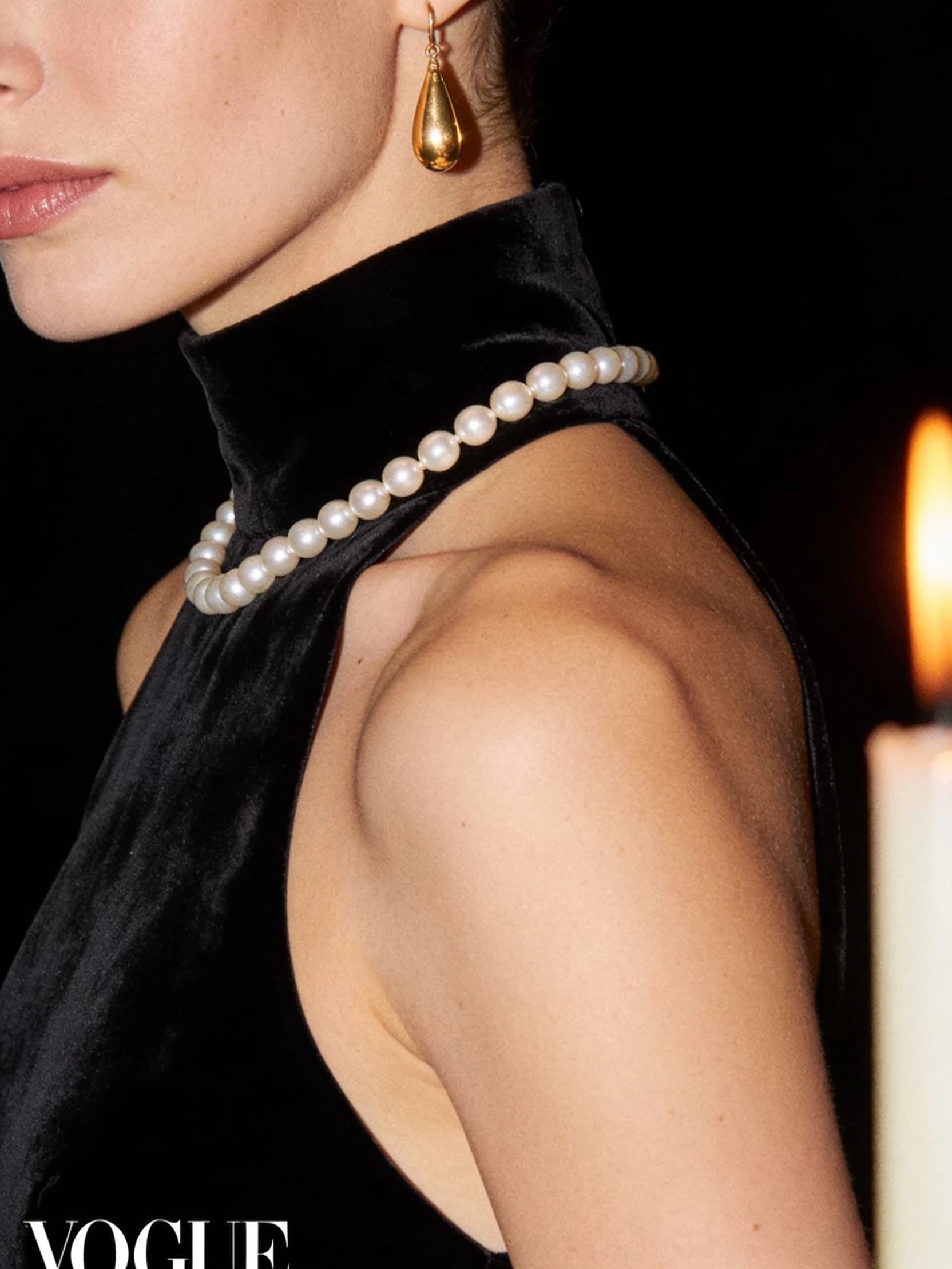 A close detail of Serena in a black velvet evening dress with a strand of pearls, cropped above the shoulders.