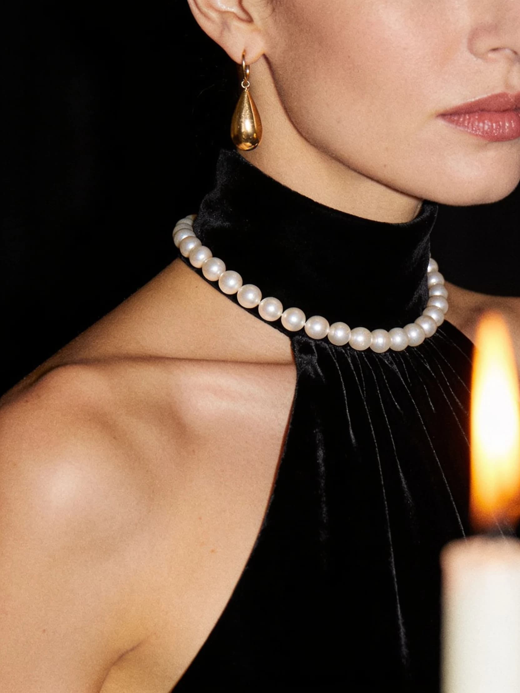 A close detail of Nadia in a black velvet evening dress with a strand of pearls, cropped above the shoulders.